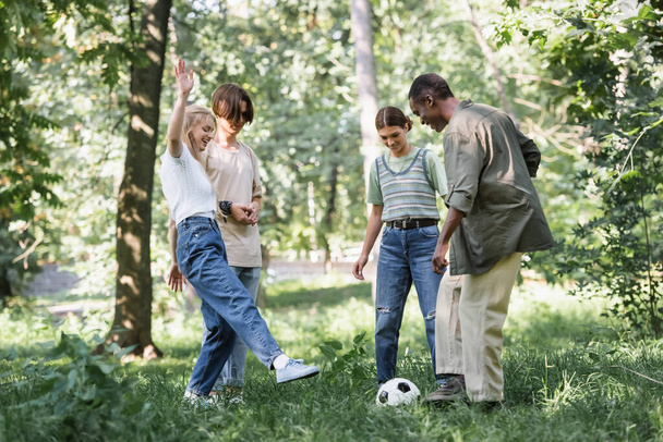 Cheerful multiethnic teenagers playing football in park  - Φωτογραφία, εικόνα