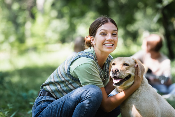Gülümseyen genç kız parkta av köpeğini kucaklıyor.  - Fotoğraf, Görsel