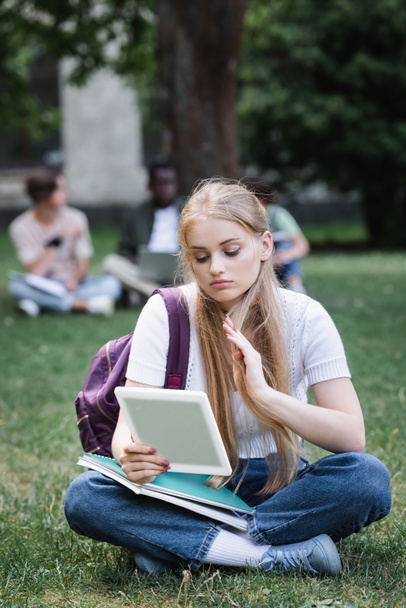 Student using digital tablet on lawn outdoors  - Foto, Imagen