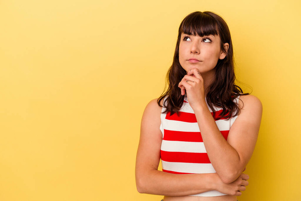 Young caucasian woman isolated on yellow background looking sideways with doubtful and skeptical expression. - Foto, afbeelding