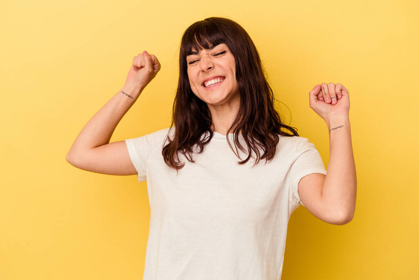 Young caucasian woman isolated on yellow background celebrating a special day, jumps and raise arms with energy. - Photo, image