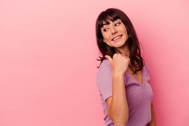 Young caucasian woman isolated on pink background points with thumb finger away, laughing and carefree. - 写真・画像