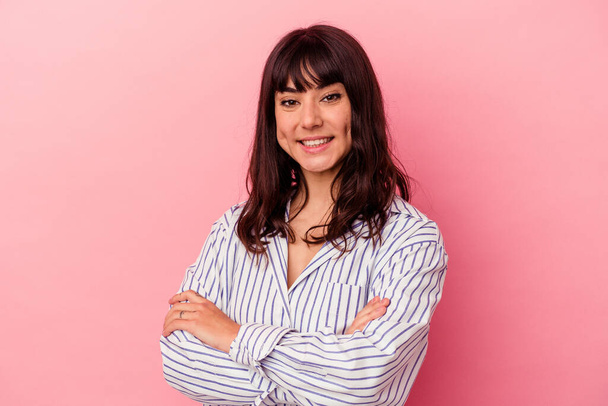 Young caucasian woman isolated on pink background who feels confident, crossing arms with determination. - Foto, Imagen