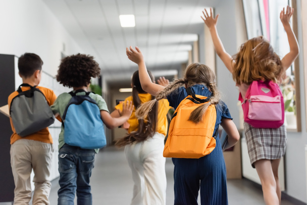 πίσω όψη πολυεθνικών μαθητών που τρέχουν στο σχολικό διάδρομο - Φωτογραφία, εικόνα