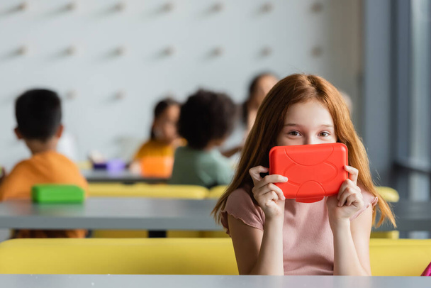 Рыжая школьница неясное лицо с коробкой обеда в закусочной - Фото, изображение