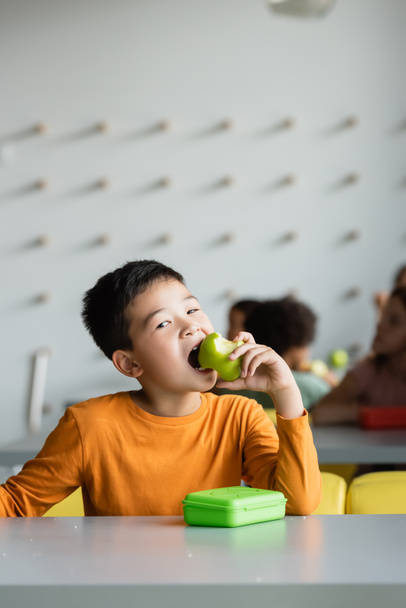 asian schoolboy eating apple in school canteen - Foto, Imagem