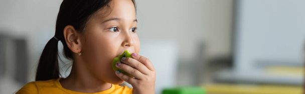 asian woman eating ripe apple during lunch break at school, banner - Photo, Image