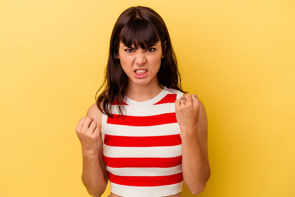 Young caucasian woman isolated on yellow background upset screaming with tense hands. - Foto, imagen