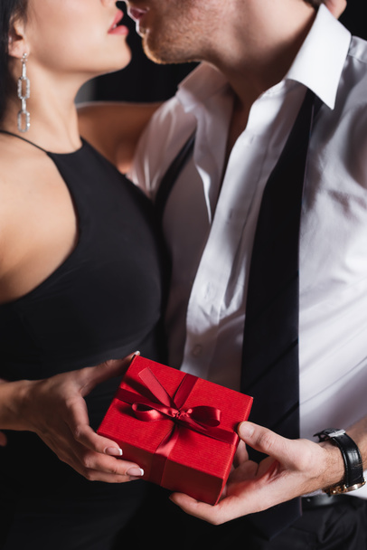 μερική άποψη του άνδρα κρατώντας κουτί δώρου και φιλιά με τη γυναίκα στο φόρεμα  - Φωτογραφία, εικόνα