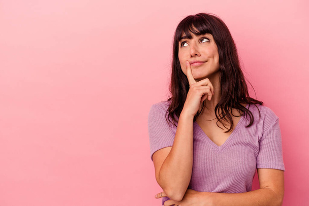 Young caucasian woman isolated on pink background looking sideways with doubtful and skeptical expression. - Foto, immagini