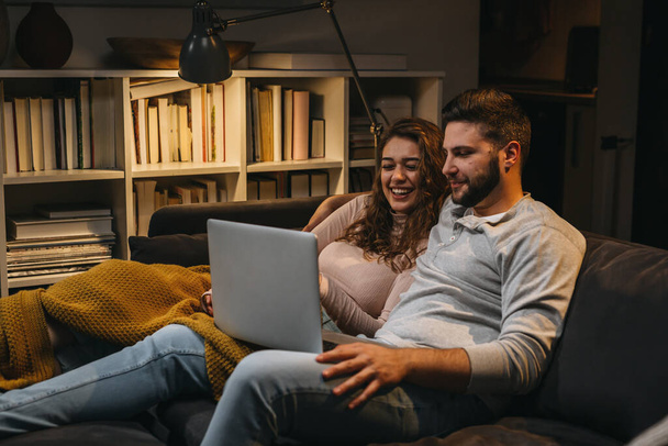 happy young couple enjoying time at home using laptop computer - Photo, Image