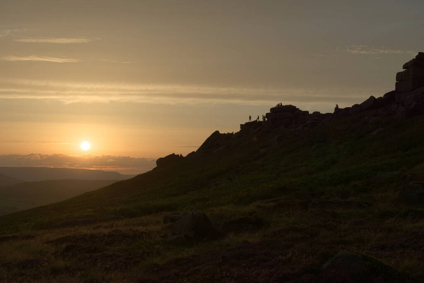 Wide angle sunset at stanage edge. Many people pursue outdoor recreational activities on top of the rocky edge. Dramatic and popular landmark - Photo, Image