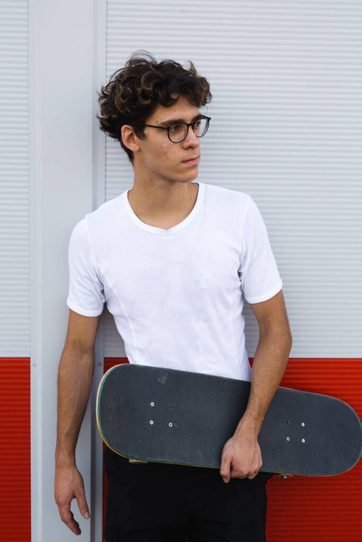 skateboarder posing against red and white wall - Photo, image