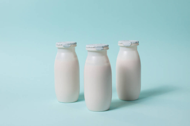 Bottles with probiotics and prebiotics dairy drink on light blue background. Bio yogurt with useful microorganisms. Production with biologically active additives. Fermentation and diet healthy food. - 写真・画像