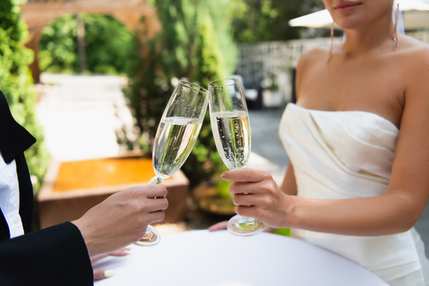 Vista ritagliata di coppia lesbica brindare con champagne durante il matrimonio all'aperto  - Foto, immagini