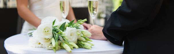 Cropped view of wedding bouquet near champagne and blurred lesbian couple outdoors, banner - Фото, изображение