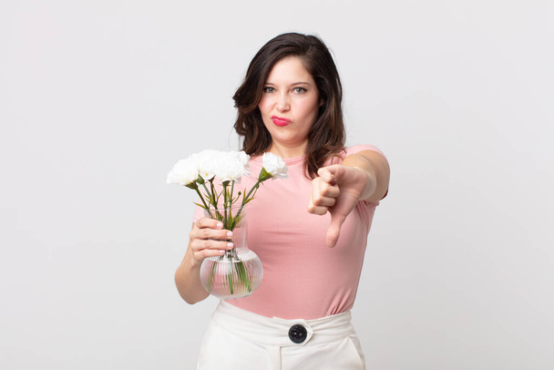 pretty woman feeling cross,showing thumbs down and holding a decorative flowers pot - Foto, Bild