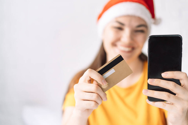 A lány fizeti a karácsonyi ajándékokat hitelkártyával online. - Fotó, kép