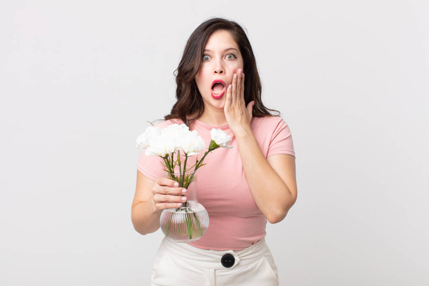 pretty woman feeling shocked and scared and holding a decorative flowers pot - Fotoğraf, Görsel