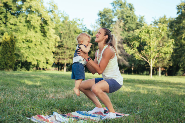mother and his baby boy do physical exercises outdoor - 写真・画像