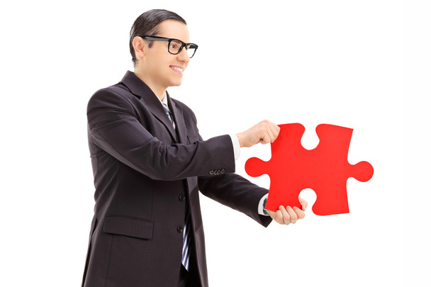 Бизнесмен держит кусочек головоломки
 - Фото, изображение