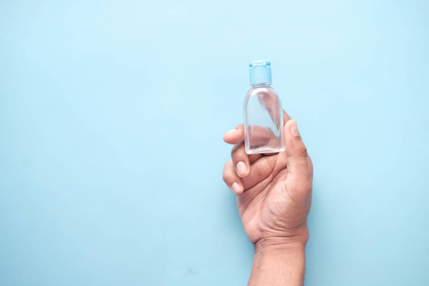  holding sanitizer liquid on blue background  - Photo, Image