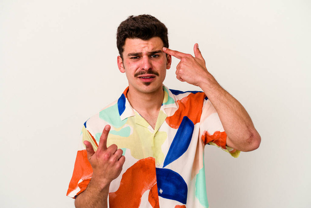 Молодой кавказский мужчина на белом фоне показывает жест разочарования указательным пальцем. - Фото, изображение