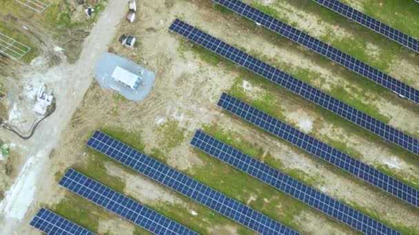 Luchtfoto van de bouw van grote elektrische centrales met vele rijen zonnepanelen op metalen frame voor het produceren van schone ecologische elektrische energie. Ontwikkeling van hernieuwbare energiebronnen. - Video