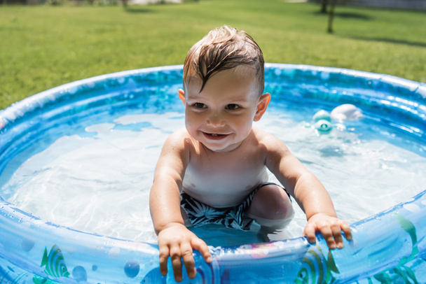 smiling toddler boy sitting in inflatable pool  - Photo, Image