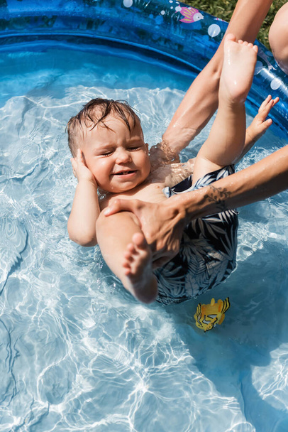 tätowierte Mutter badet Kleinkind-Sohn in aufblasbarem Pool - Foto, Bild