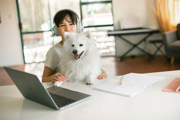 niña bastante caucásica con un perro haciendo aprendizaje en línea utilizando el ordenador portátil, la educación en casa, la educación a distancia - Foto, imagen