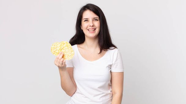 pretty woman looking happy and pleasantly surprised and holding a diet rice cakes - Photo, image