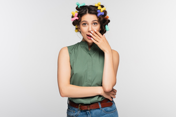surprised young woman with colorful hair curlers isolated on grey - Fotografie, Obrázek