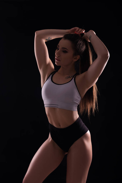 Fit brunette woman doing exercises in studio on neutral background. Flawless sporty body in sportswear outfit. Space for text - Φωτογραφία, εικόνα