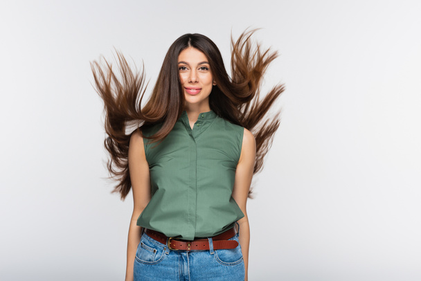happy young woman with shiny hair in air isolated on grey - Фото, зображення