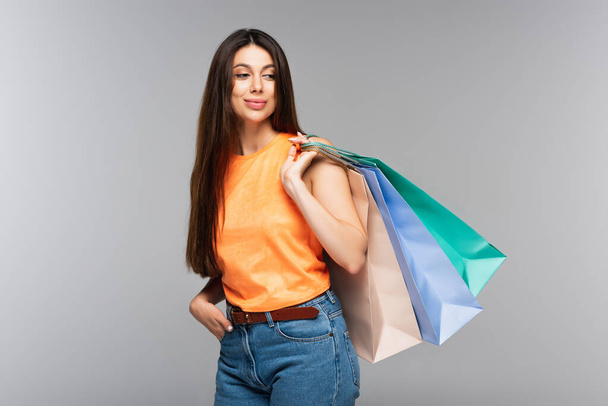 smiling young woman holding shopping bags isolated on grey  - Fotografie, Obrázek