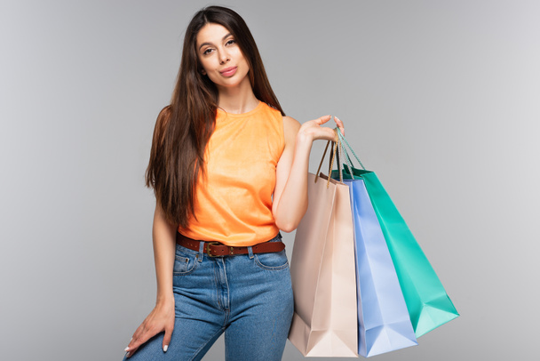 brunette young woman holding shopping bags isolated on grey  - Foto, Imagem