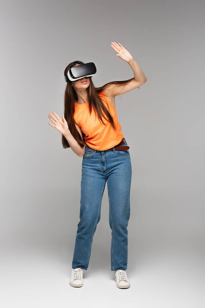 full length of young woman in vr headset on grey - Fotografie, Obrázek