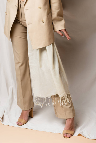 partial view of woman in beige suit and heels standing on drapery - Photo, Image