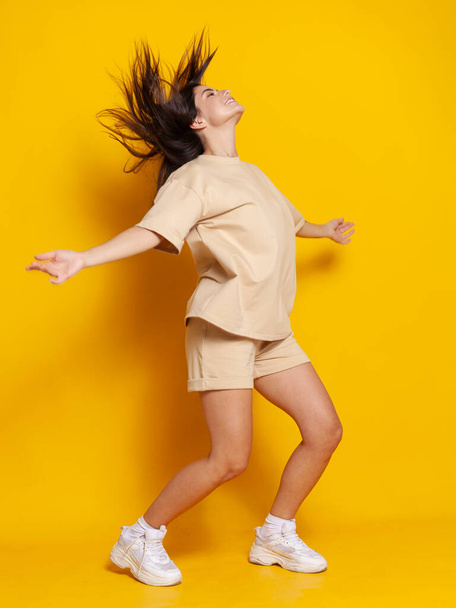 beautiful brunette dancing hip hop on bright background - Photo, image