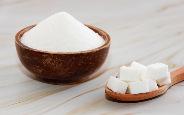 white granulated and sugar pieces in a wooden spoon - Photo, Image
