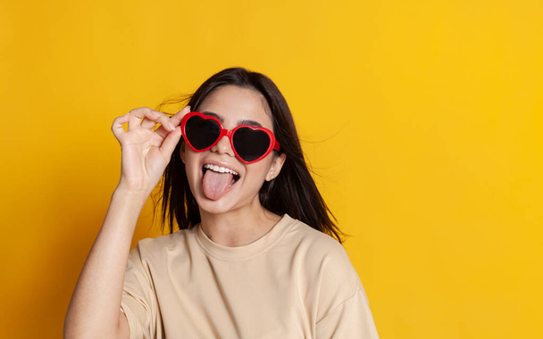 beautiful brunette in bright glasses smiling on a yellow background - Fotografie, Obrázek