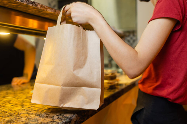 Courier delivery food service at home. Woman courier delivered the order no name bag with food. - Foto, imagen