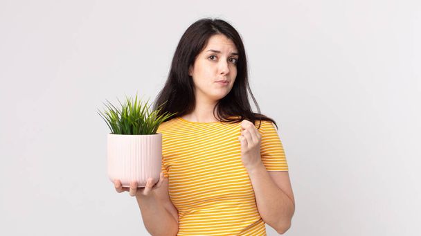 pretty woman looking arrogant, successful, positive and proud and holding a decorative plant - Foto, imagen