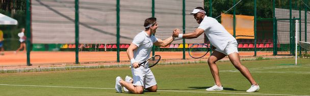 Возбужденные мультиэтнические теннисисты пожимают руку на корте, баннер  - Фото, изображение