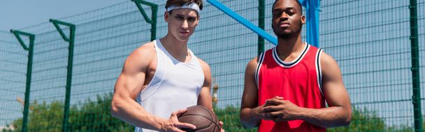 Interrassische Basketballer blicken auf Spielplatz in die Kamera, Banner  - Foto, Bild