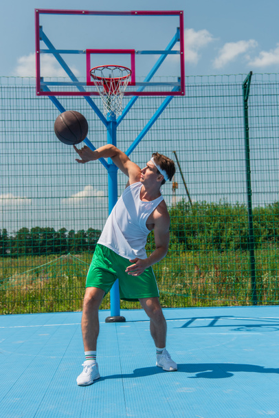 Sportive player spinning basketball ball on playground  - Zdjęcie, obraz