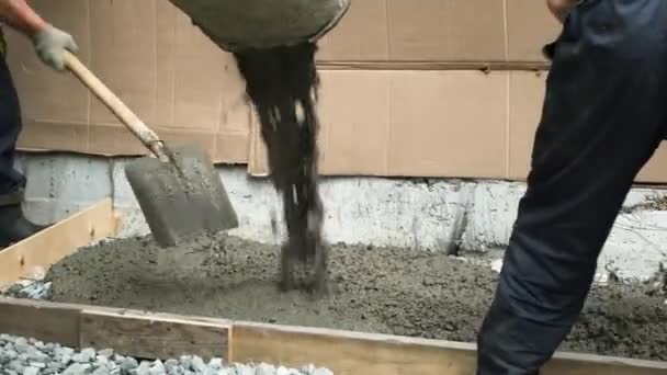 Os trabalhadores estão derramando concreto na cofragem da casa. Trabalhadores ancinho e nivelar o concreto na cofragem da casa. - Filmagem, Vídeo