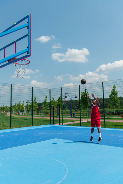 African american sportsman jumping and throwing basketball ball in hoop  - Foto, Bild