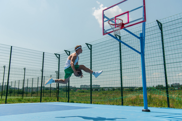 Side view of sportsman playing streetball on outdoor playground  - Zdjęcie, obraz